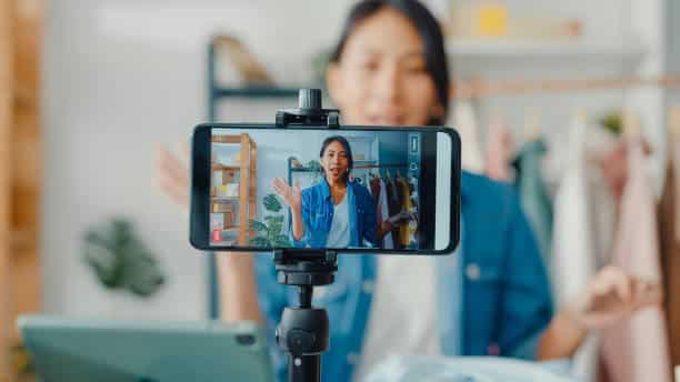 user generated content strategy - woman sat in front of a phone recording content